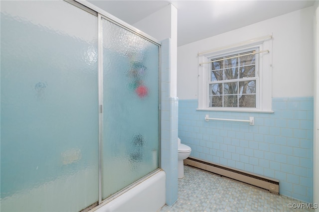 bathroom featuring tile walls, a wainscoted wall, bath / shower combo with glass door, toilet, and baseboard heating