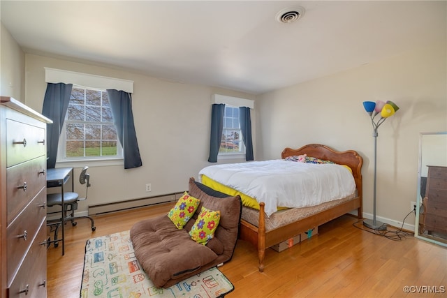 bedroom featuring baseboards, light wood finished floors, visible vents, and a baseboard radiator