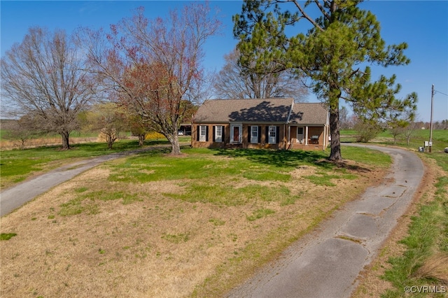 view of front facade featuring aphalt driveway, a porch, and a front yard