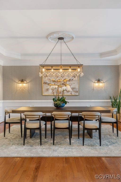 dining room with a raised ceiling, crown molding, and wood finished floors