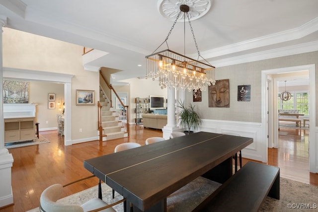 dining room with ornamental molding, decorative columns, a chandelier, stairway, and wood finished floors
