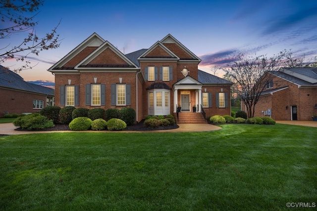 view of front of property featuring brick siding and a lawn