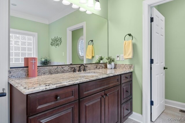 bathroom featuring vanity, baseboards, ornamental molding, and visible vents