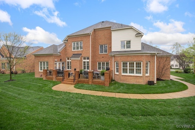 rear view of property with a yard, brick siding, and a shingled roof