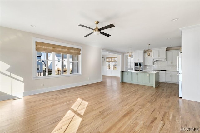 unfurnished living room featuring a ceiling fan, baseboards, light wood finished floors, and recessed lighting