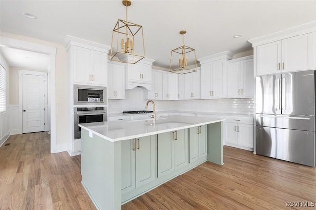 kitchen with light wood finished floors, light countertops, white cabinets, and appliances with stainless steel finishes