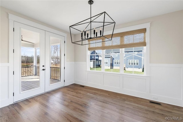 unfurnished dining area featuring wood finished floors, french doors, and plenty of natural light