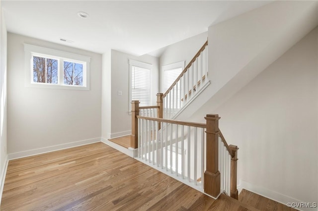 staircase featuring baseboards, visible vents, and wood finished floors