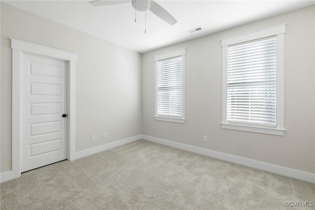 empty room with baseboards, visible vents, ceiling fan, and carpet flooring