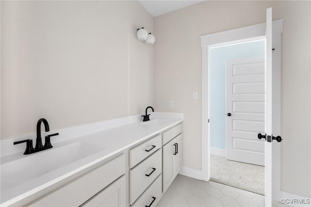 full bath featuring baseboards, double vanity, and a sink
