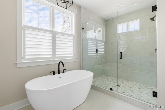 bathroom featuring a soaking tub, baseboards, and a shower stall