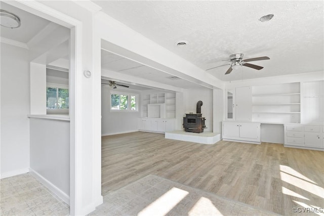 201 Winston Ave, Colonial Heights, VA 23834 - unfurnished living room featuring a ceiling fan, a wood stove, baseboards, a textured ceiling, and light wood finished floors