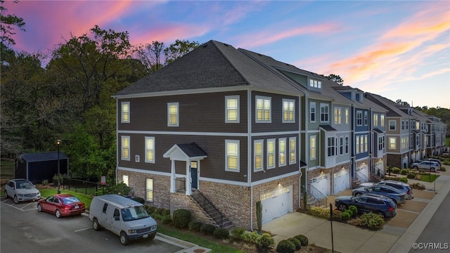 exterior space featuring brick siding, driveway, a shingled roof, and a garage