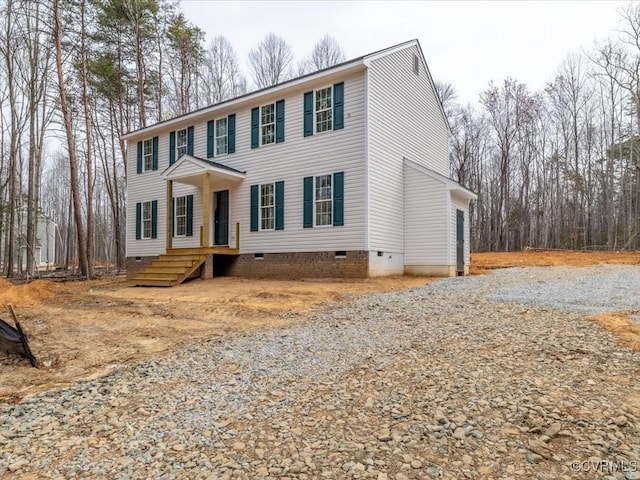 colonial-style house featuring crawl space, gravel driveway, and an attached garage