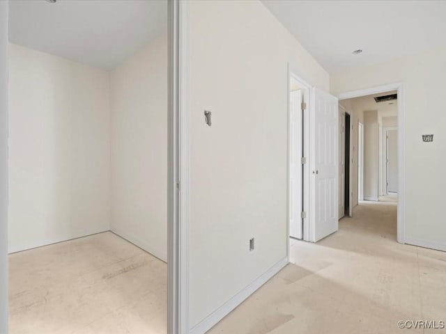 hallway featuring unfinished concrete flooring and baseboards