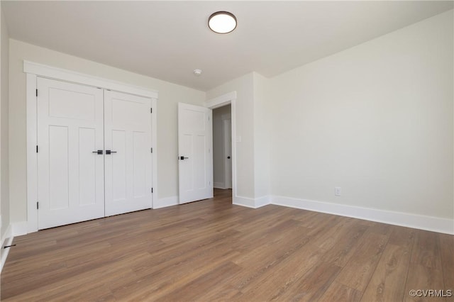 unfurnished bedroom with wood finished floors, a closet, and baseboards