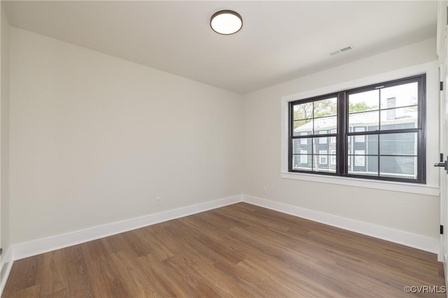 unfurnished room featuring dark wood-style floors, baseboards, and visible vents
