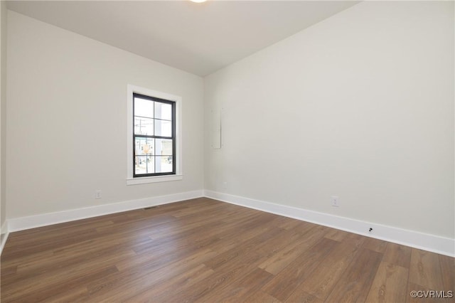 unfurnished room with dark wood finished floors, visible vents, and baseboards