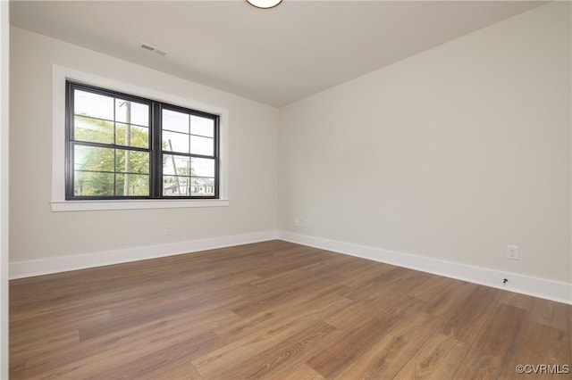 unfurnished room featuring baseboards, wood finished floors, and visible vents