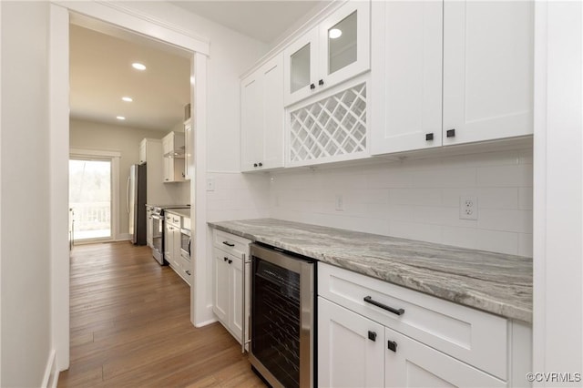 kitchen with white cabinets, recessed lighting, wine cooler, tasteful backsplash, and appliances with stainless steel finishes