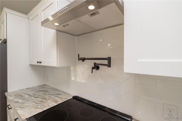 kitchen with backsplash, white cabinetry, exhaust hood, light stone counters, and range