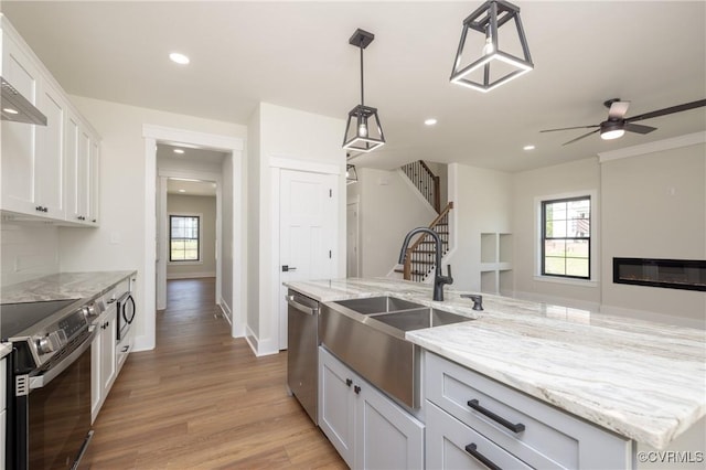 kitchen featuring a sink, light wood-type flooring, stainless steel appliances, white cabinetry, and recessed lighting