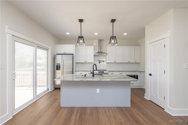 kitchen featuring wood finished floors, wall chimney exhaust hood, stainless steel appliances, and a sink