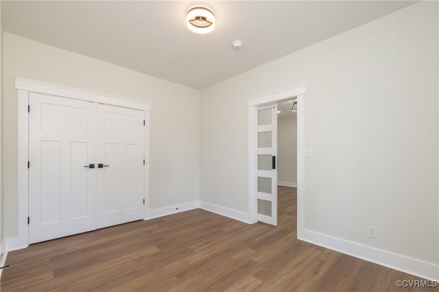 unfurnished bedroom with wood finished floors, a closet, and baseboards
