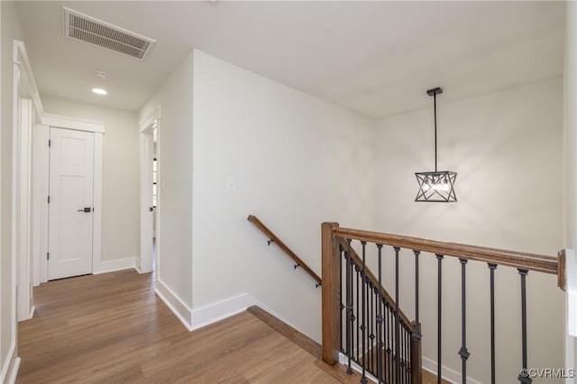 stairway with baseboards, wood finished floors, visible vents, and recessed lighting