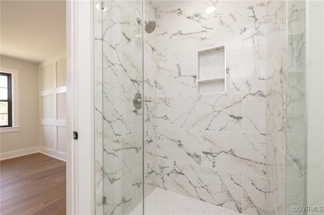 full bath featuring wood finished floors, baseboards, and a marble finish shower