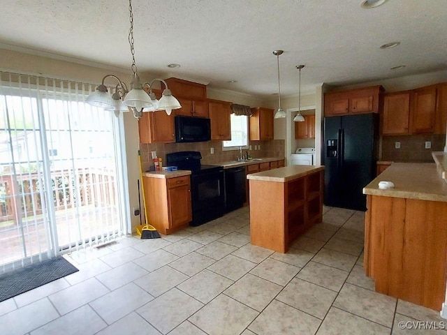 kitchen with washer / clothes dryer, black appliances, a center island, a sink, and backsplash