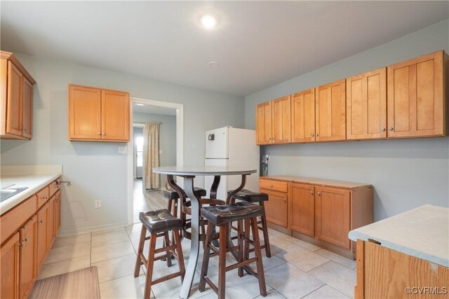 3057 Maury St, Richmond, VA 23224 - kitchen featuring light tile patterned floors, light countertops, freestanding refrigerator, and baseboards