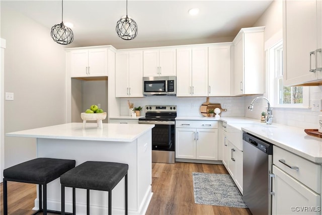 12036 Corte Castle Rd, Chesterfield, VA 23838 - kitchen featuring appliances with stainless steel finishes, a breakfast bar, backsplash, white cabinets, and wood finished floors