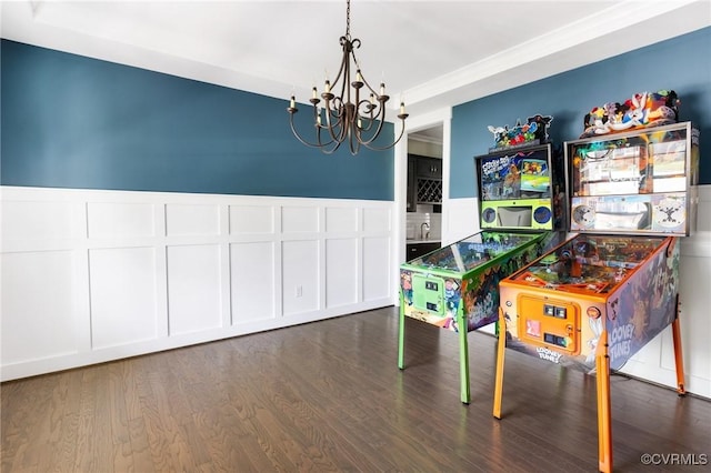 rec room with wood finished floors, a decorative wall, a notable chandelier, and wainscoting