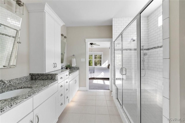 full bathroom featuring a ceiling fan, tile patterned floors, a stall shower, vanity, and baseboards