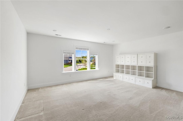 unfurnished room featuring light colored carpet and baseboards