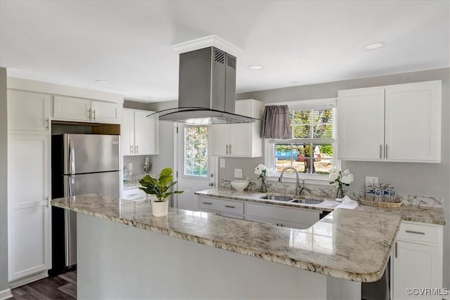 kitchen with island range hood, white cabinetry, a sink, and freestanding refrigerator