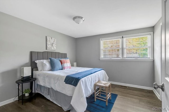 bedroom with baseboards, visible vents, and wood finished floors