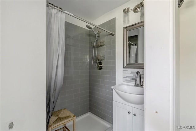 bathroom featuring a tile shower, tasteful backsplash, and vanity
