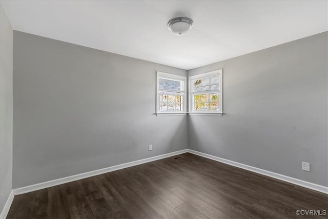 spare room featuring baseboards and wood finished floors