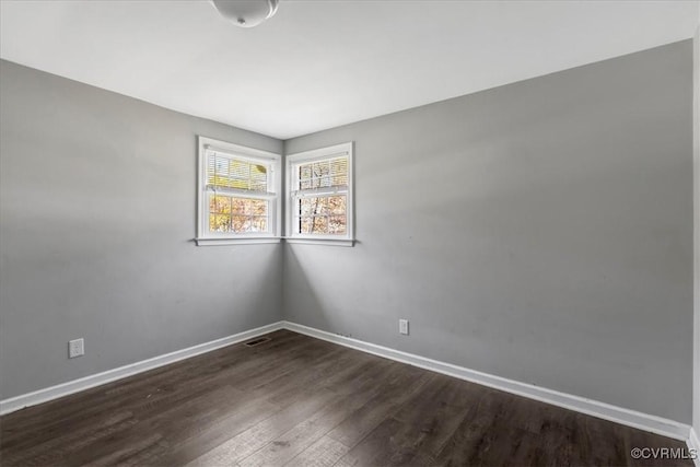 empty room with dark wood-type flooring and baseboards