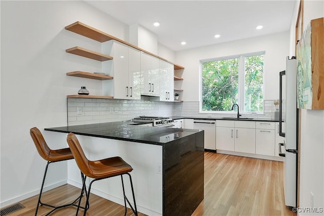 kitchen featuring open shelves, visible vents, a peninsula, and white dishwasher