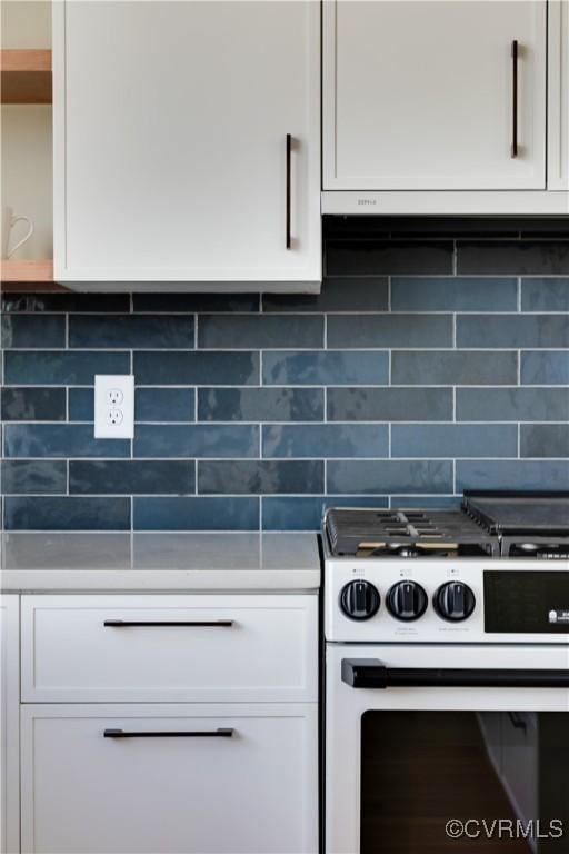 kitchen featuring white cabinets, decorative backsplash, and white range with gas stovetop