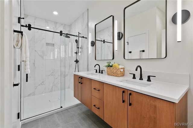bathroom with double vanity, a marble finish shower, and a sink