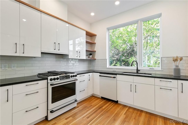 kitchen with range with gas cooktop, open shelves, white dishwasher, a sink, and white cabinets