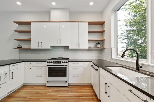 kitchen with open shelves, white cabinets, appliances with stainless steel finishes, and a sink