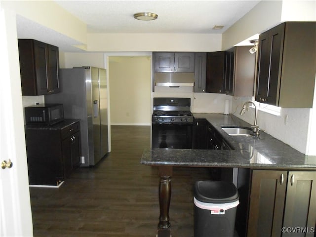 kitchen featuring dark brown cabinets, dark stone counters, a sink, and black appliances