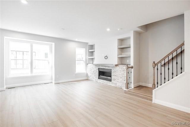 unfurnished living room featuring light wood-type flooring, baseboards, stairs, and recessed lighting