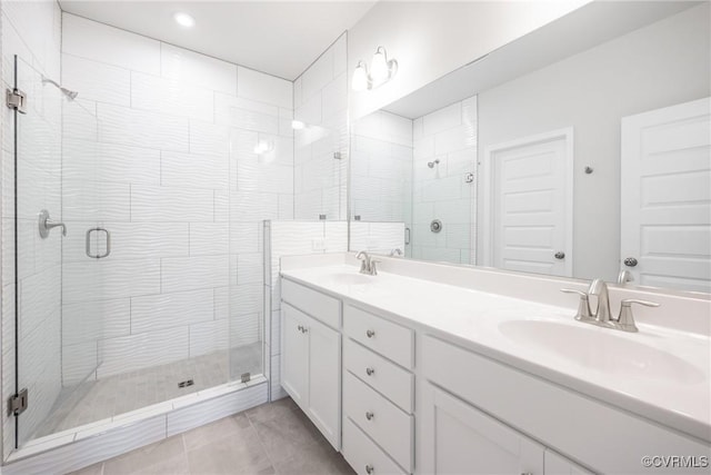 bathroom featuring a shower stall, tile patterned flooring, double vanity, and a sink