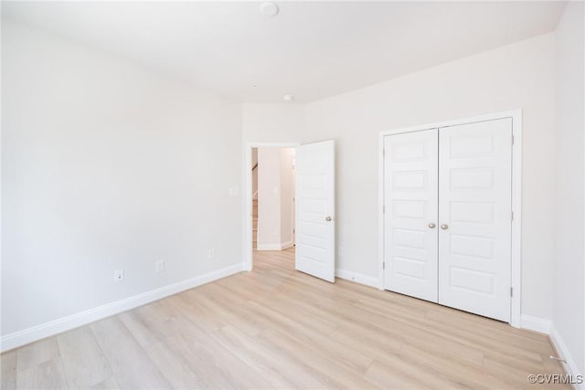 unfurnished bedroom with a closet, light wood-type flooring, and baseboards